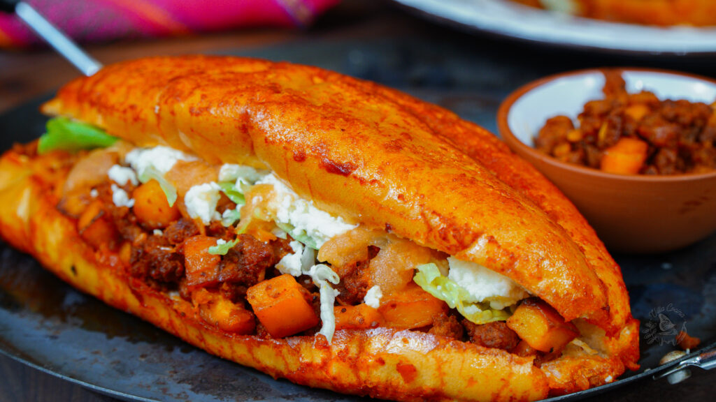 this pambazo is a mexican torta where the bread is drenched in guajilo sauce