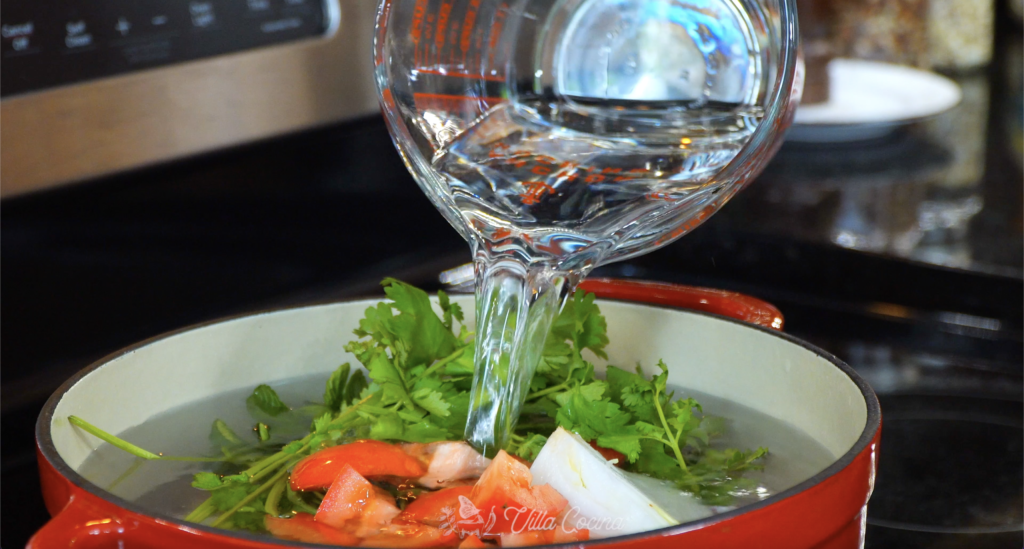 water being poured into a pot with aromatics