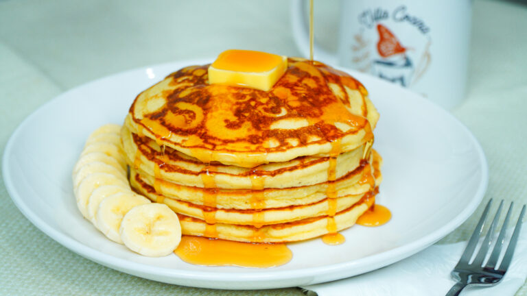 Classic pancakes served with a portion of fruit, butter and maple syrup