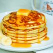 Classic pancakes served with a portion of fruit, butter and maple syrup