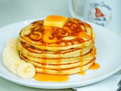 Classic pancakes served with a portion of fruit, butter and maple syrup