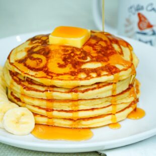 Classic pancakes served with a portion of fruit, butter and maple syrup