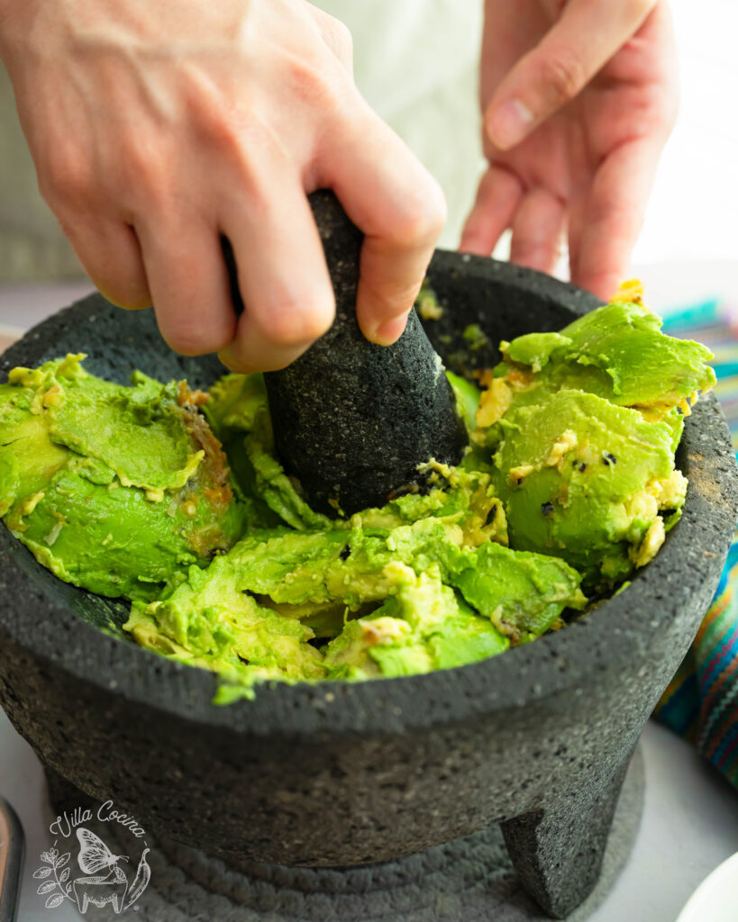 Avocadoes being crushed with a pestle