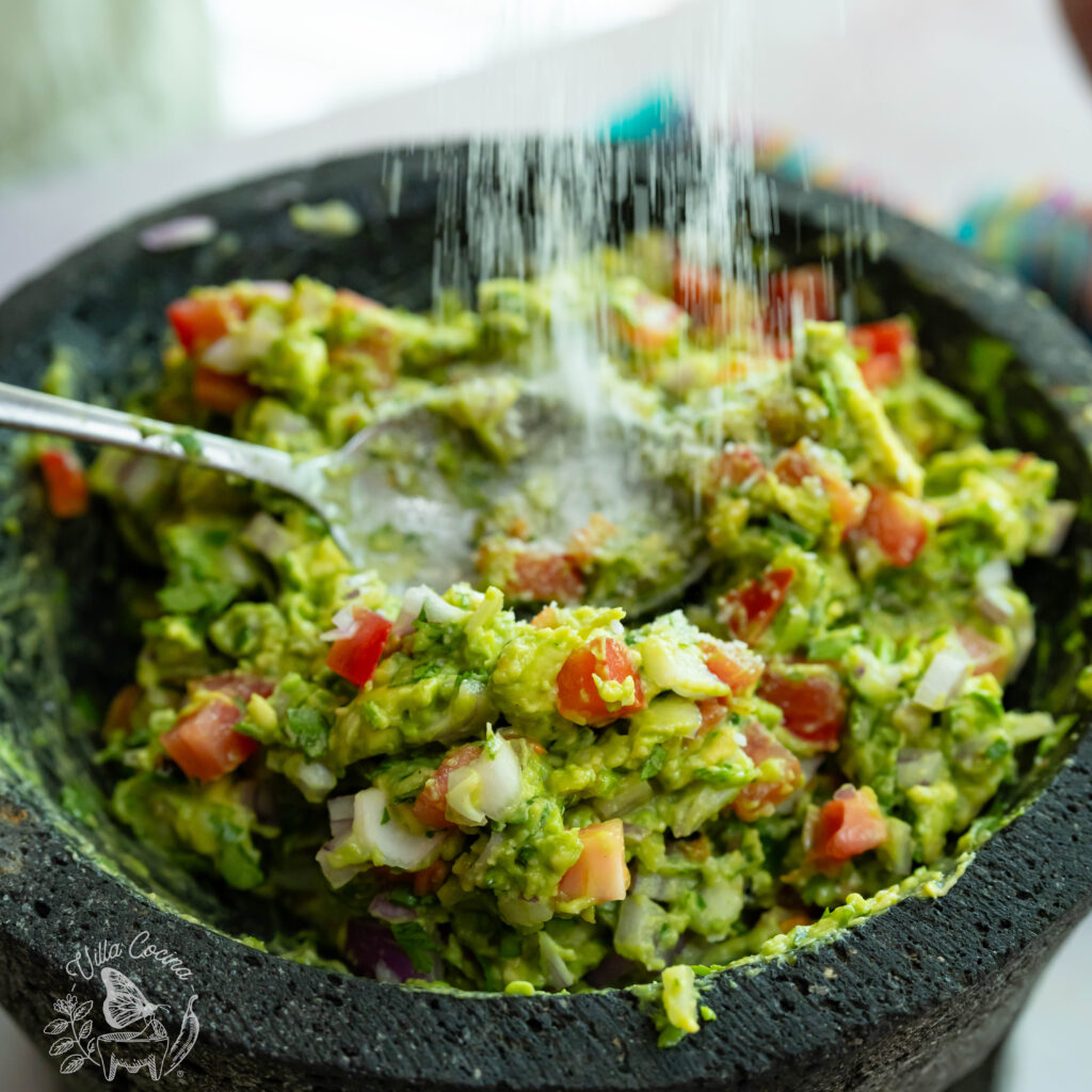 Garlic roasted guacamole being sprinkled with salt