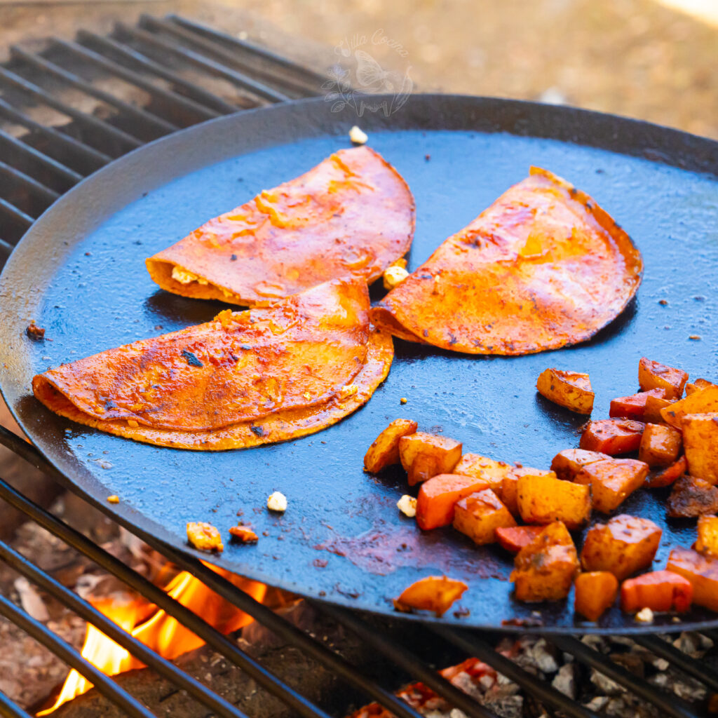 Enchiladas Rojas frying on a comal