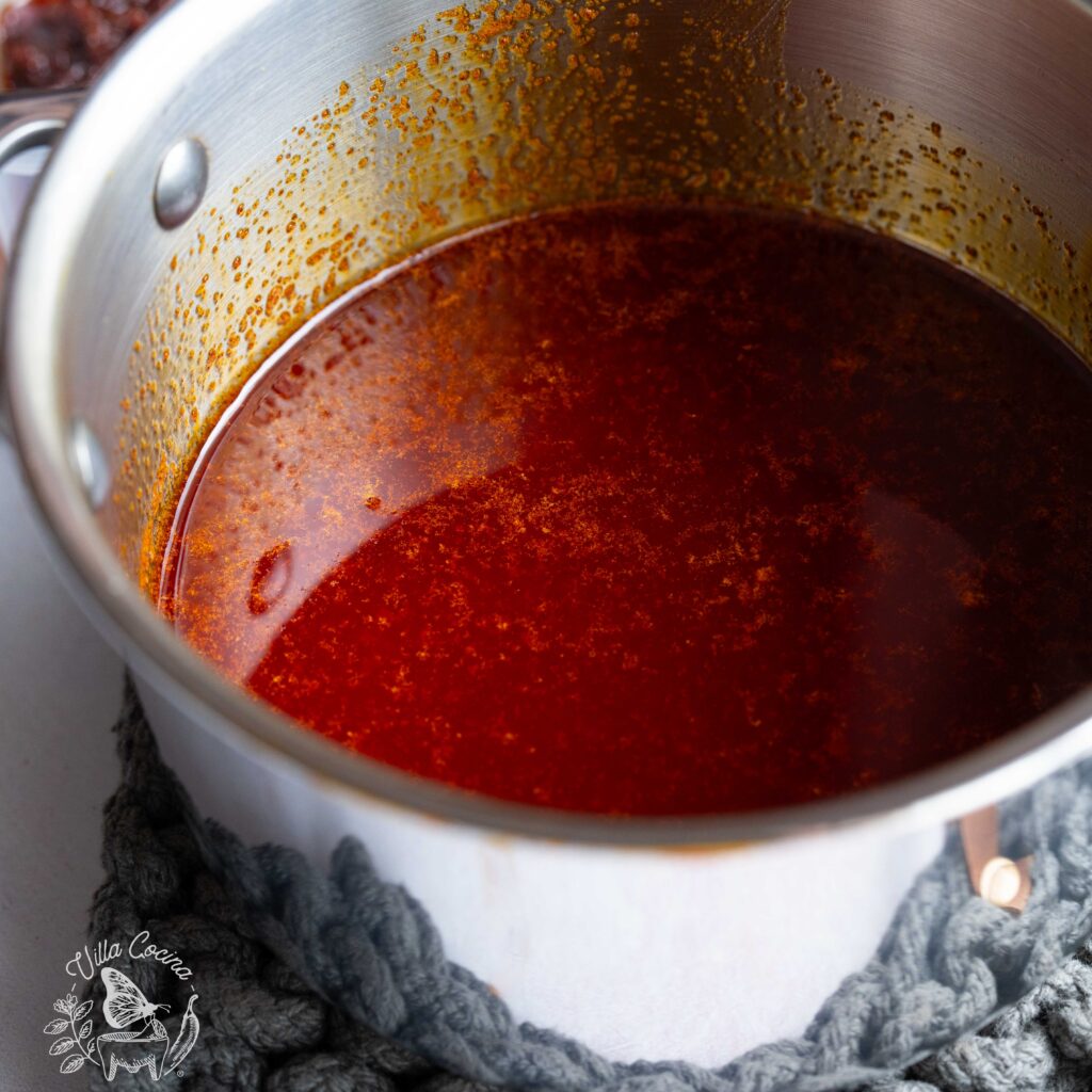 Strained guajillo chili oil inside a small pot.