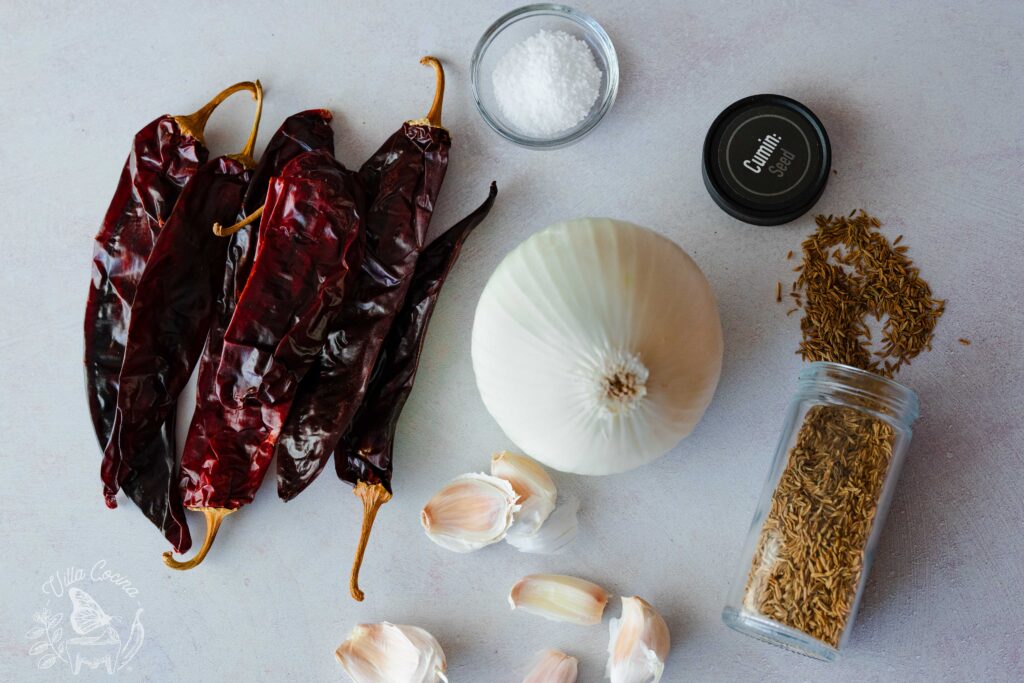 Displayed chili oil ingredients: cumin, salt, garlic, onions, and guajillo peppers.