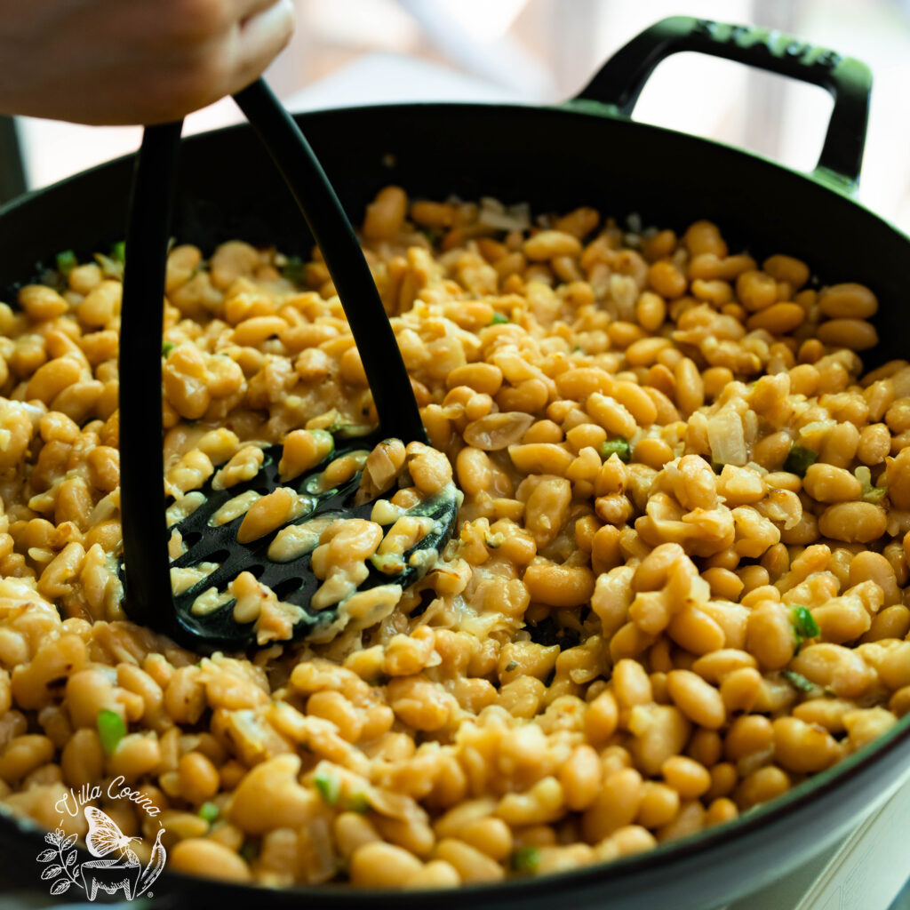 mashing peruano beans with a potato masher