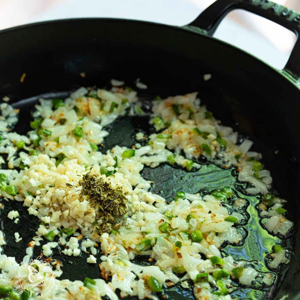 Oregano ready to be toasted in a pan with sautéed onion