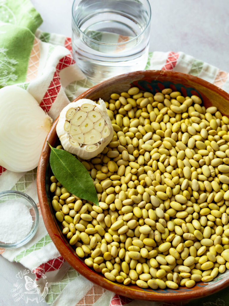 Raw perunao beans along with salt, onion, bayleaf, garlic, and a glass of water.