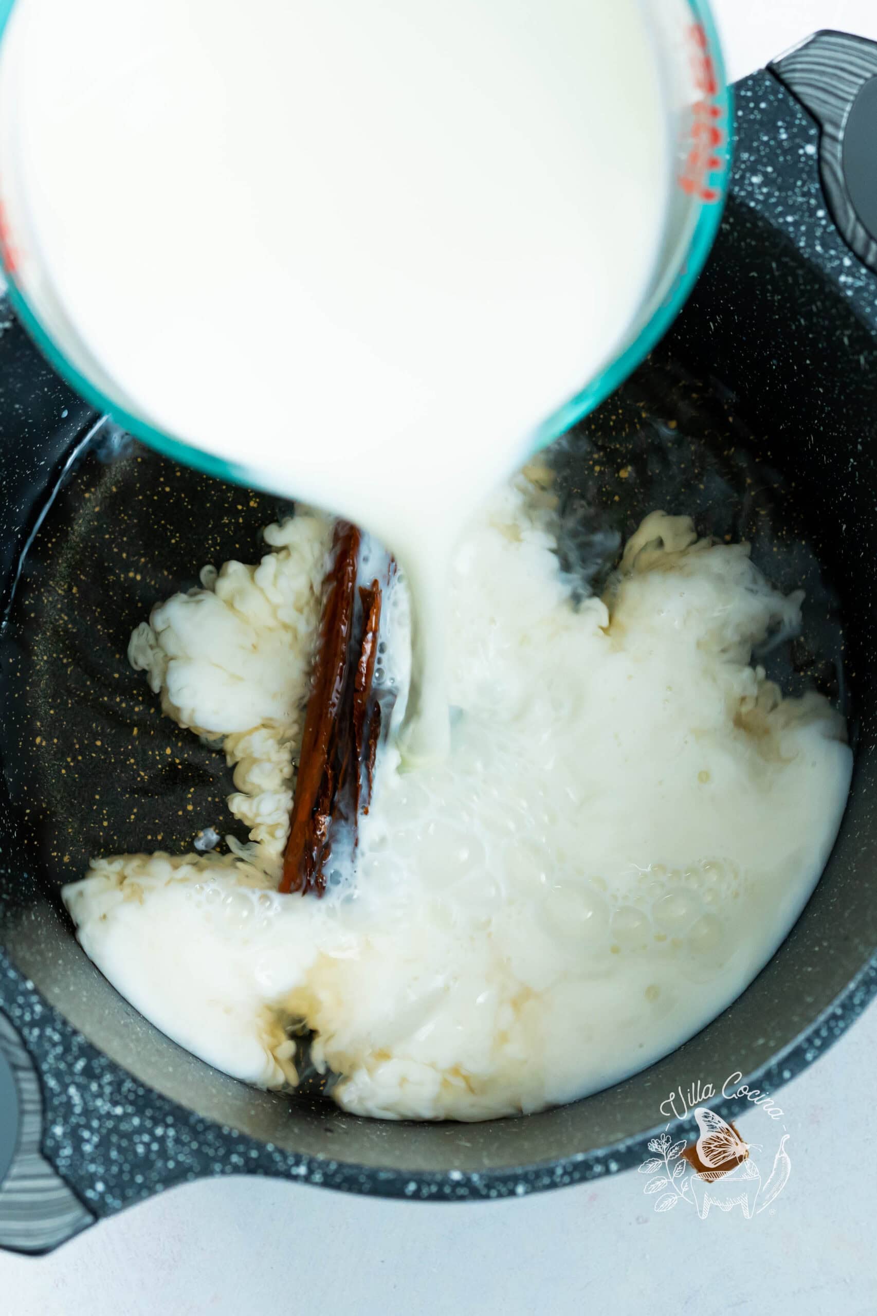 Combining milk with cinnamon-infused water to prepare a smooth caramel base for atole de café. 