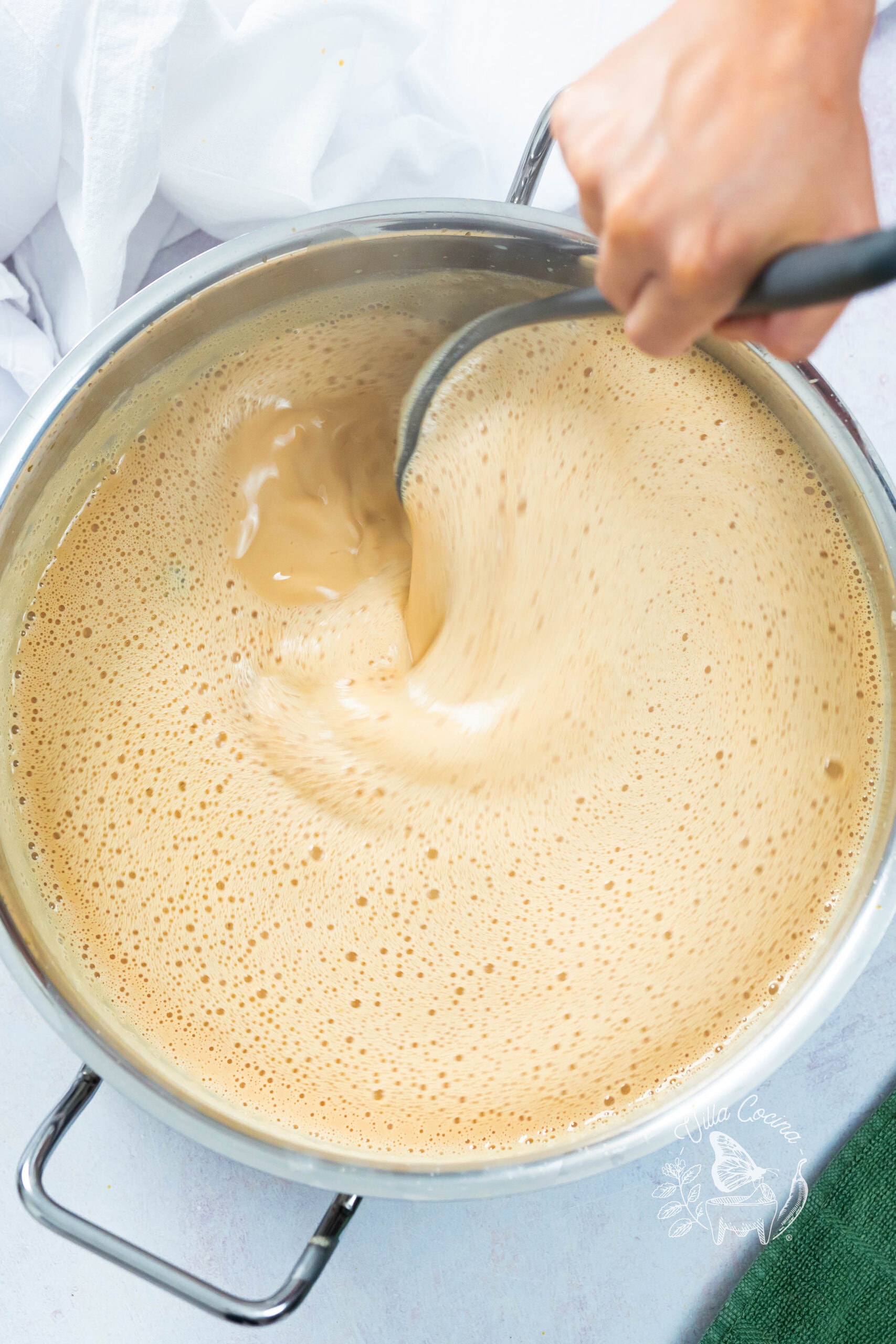 Stirring atole as it thickens to a smooth, creamy consistency.