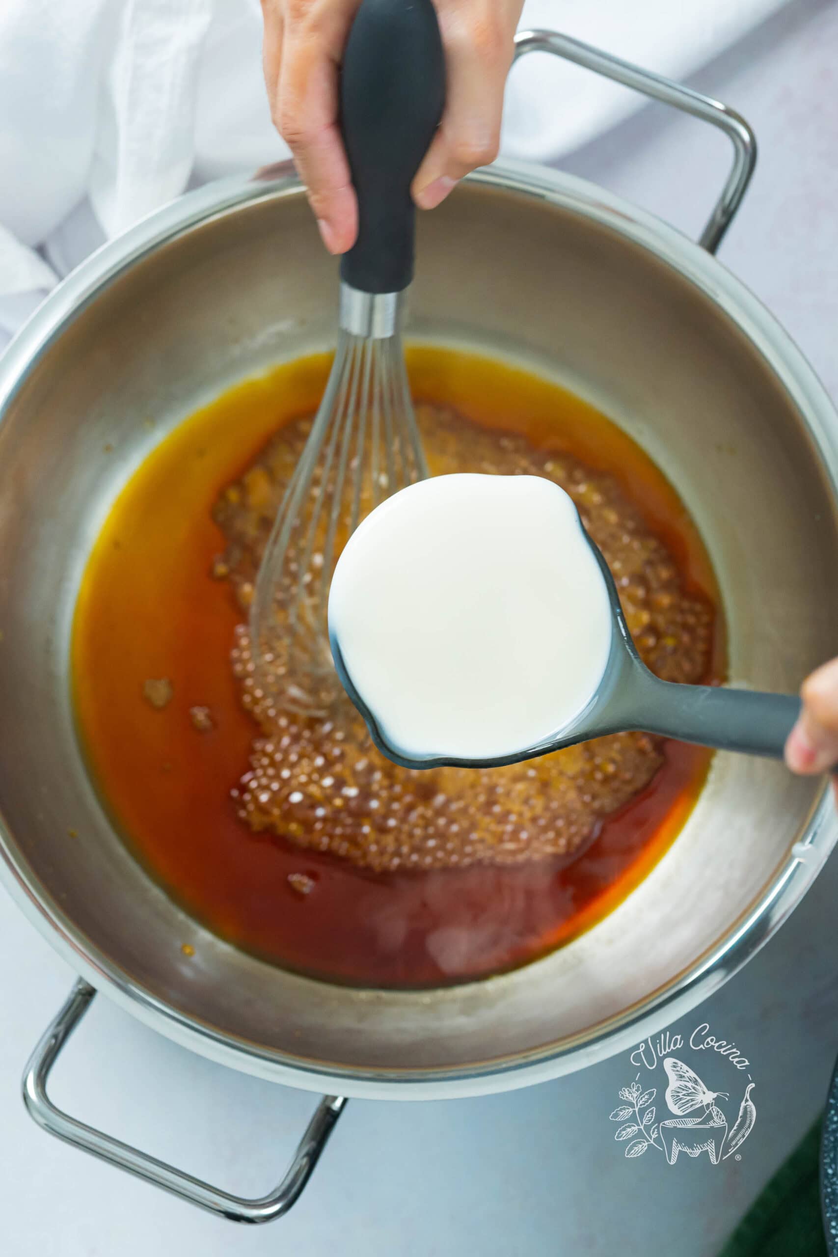 Warm milk being carefully added to caramel to deglaze and form the base for atole de café.