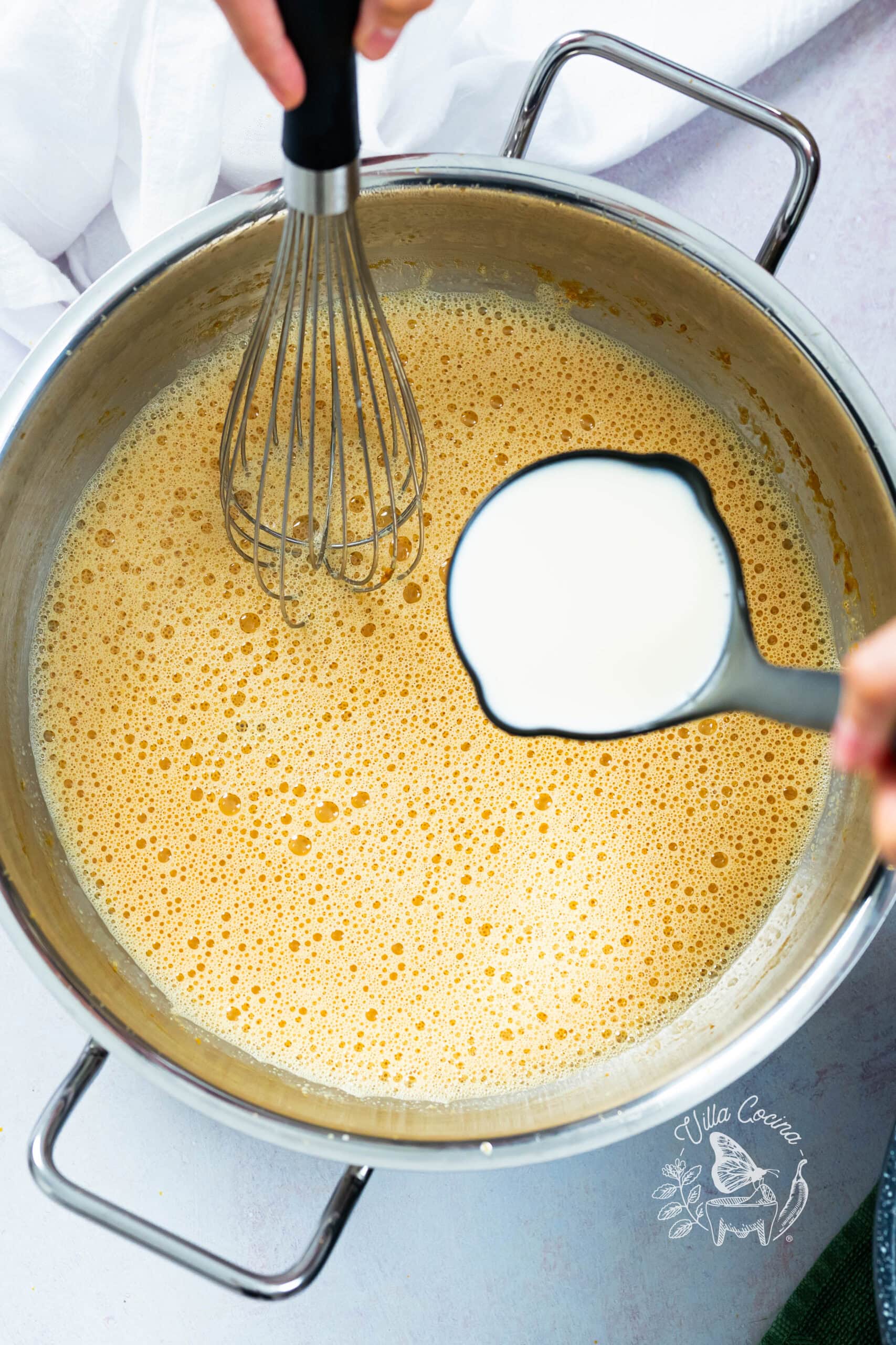 Adding milk to caramel after the initial bubbling has settled.