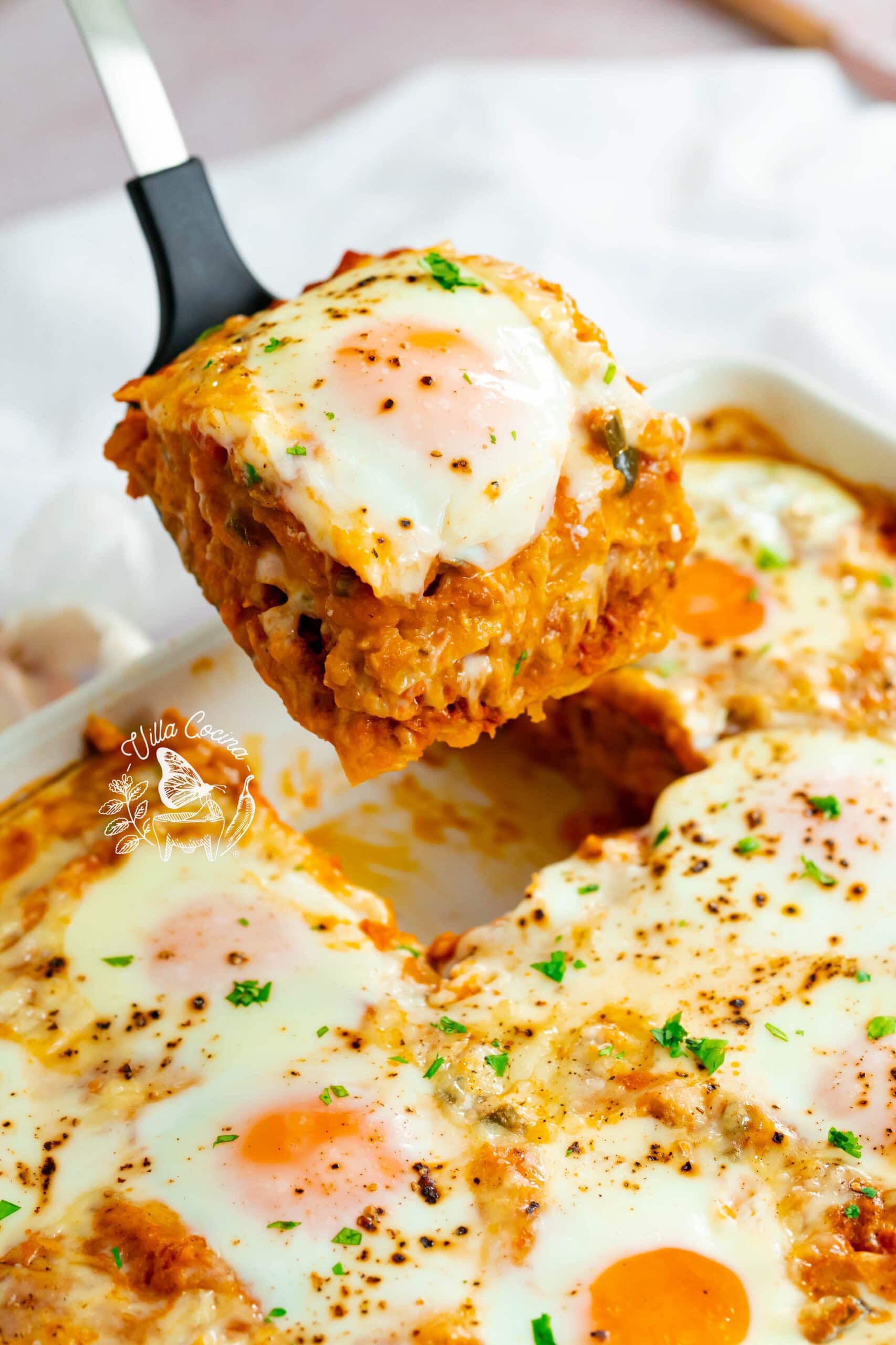 Piece of huevos rancheros casserole being lifted from the dish.