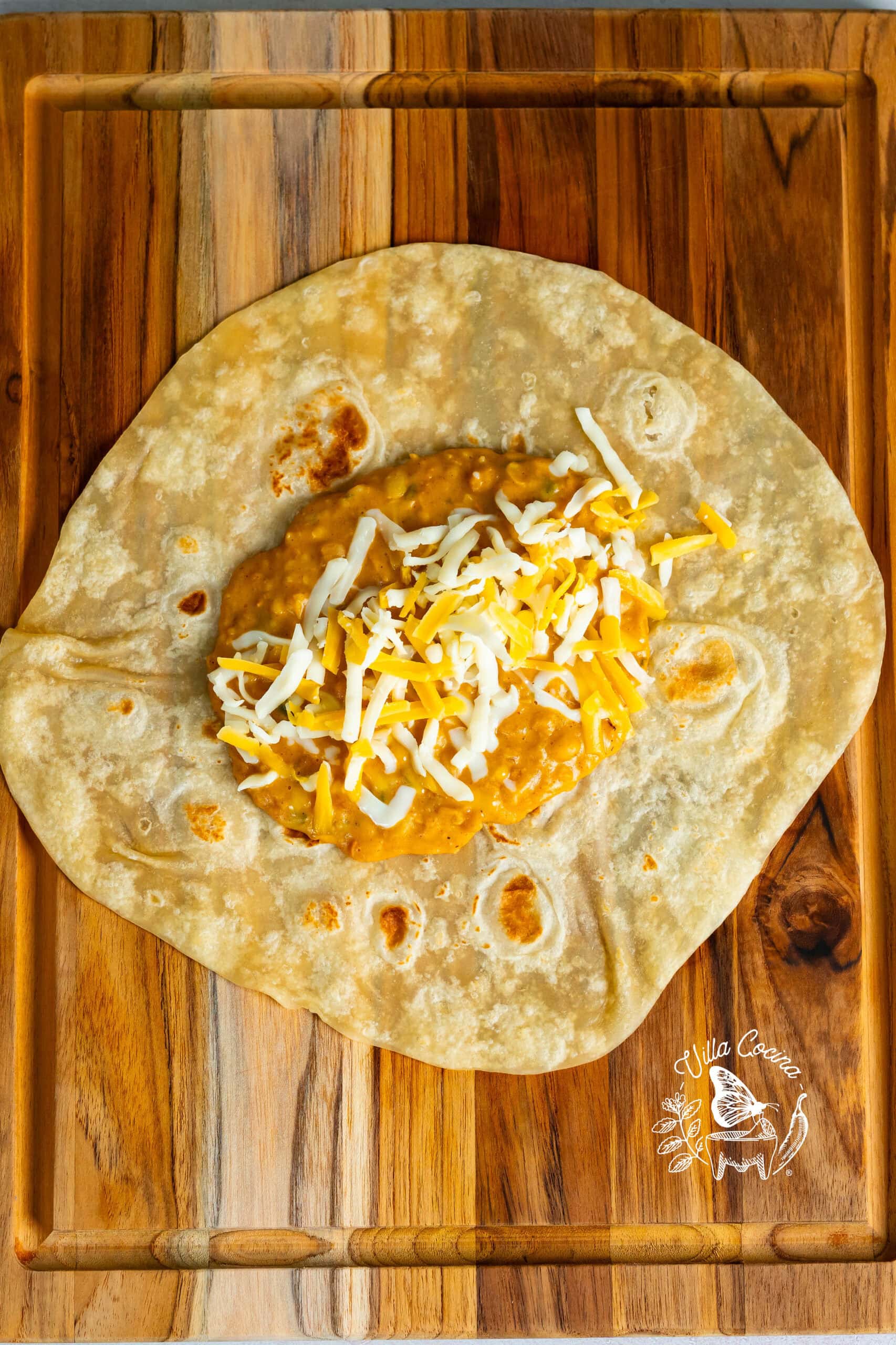 Add refried beans and cheese to burrito.
